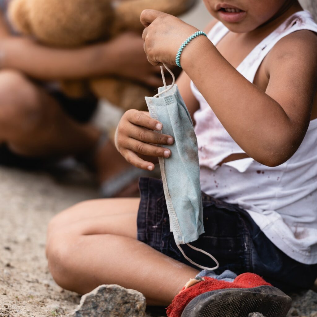 cropped view of poor african american kid holding dirty medical mask near sister